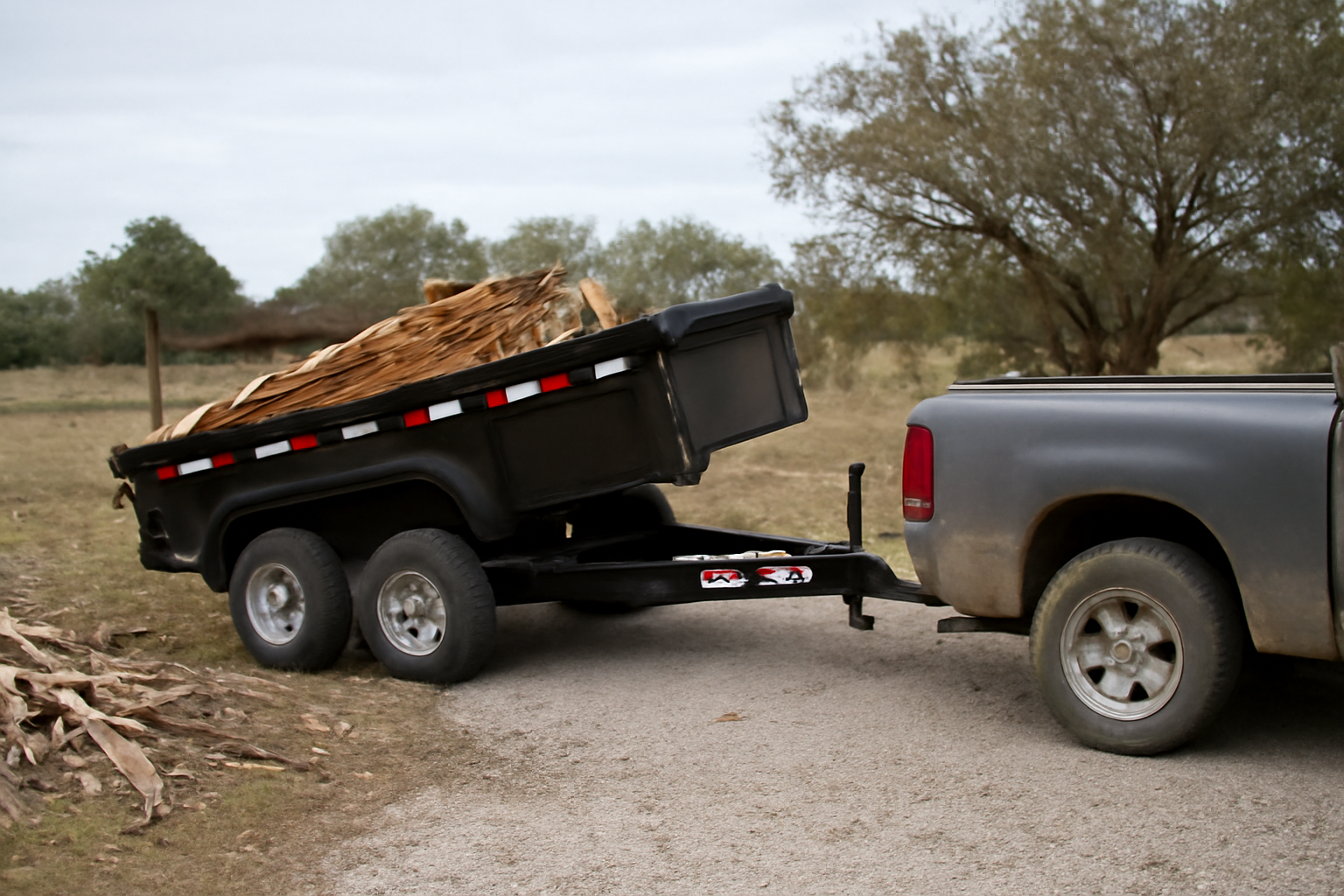 14k hydraulic dump trailer hitched to a pickup truck during a debris cleanout in rural North Texas